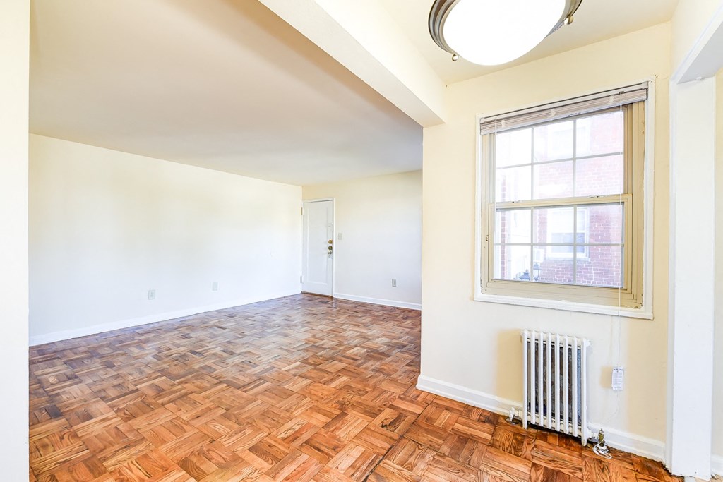 vacant living area with hardwood flooring and large windows at richman apartments in washington dc