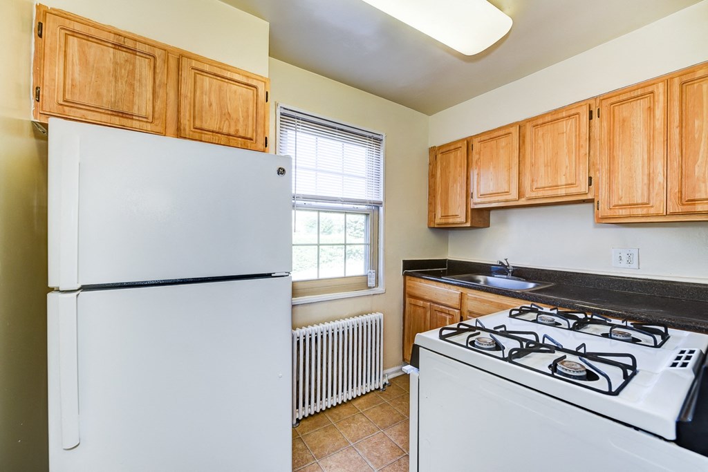 kitchen with wood cabinetry, tile flooring and window at the richman apartments in washington dc