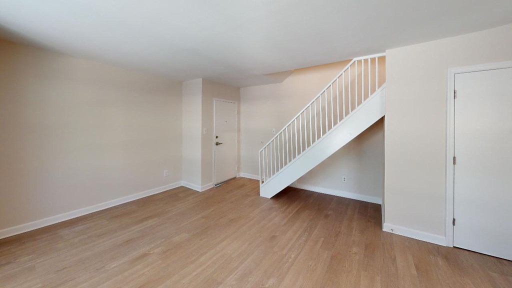 an empty living room with a staircase in the background