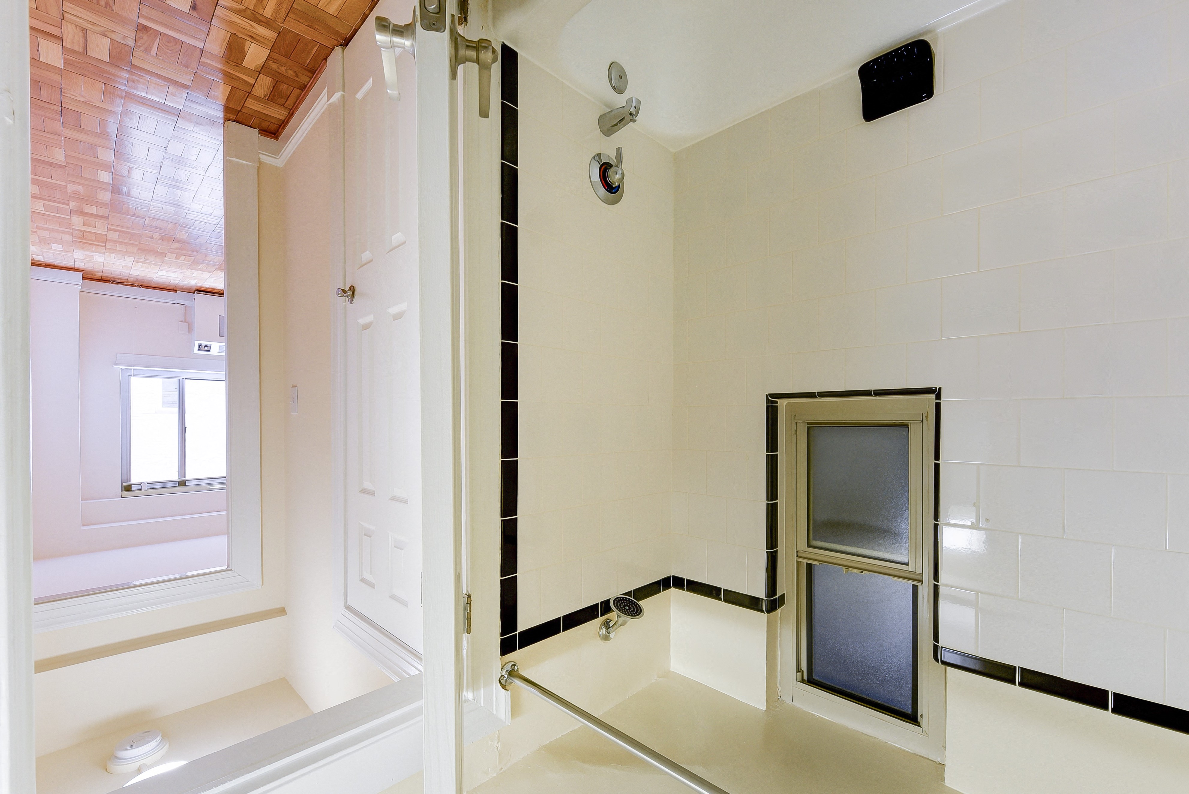 bathroom with tub, window, tile detail and view of bedroom at sherry hall apartments in washington dc