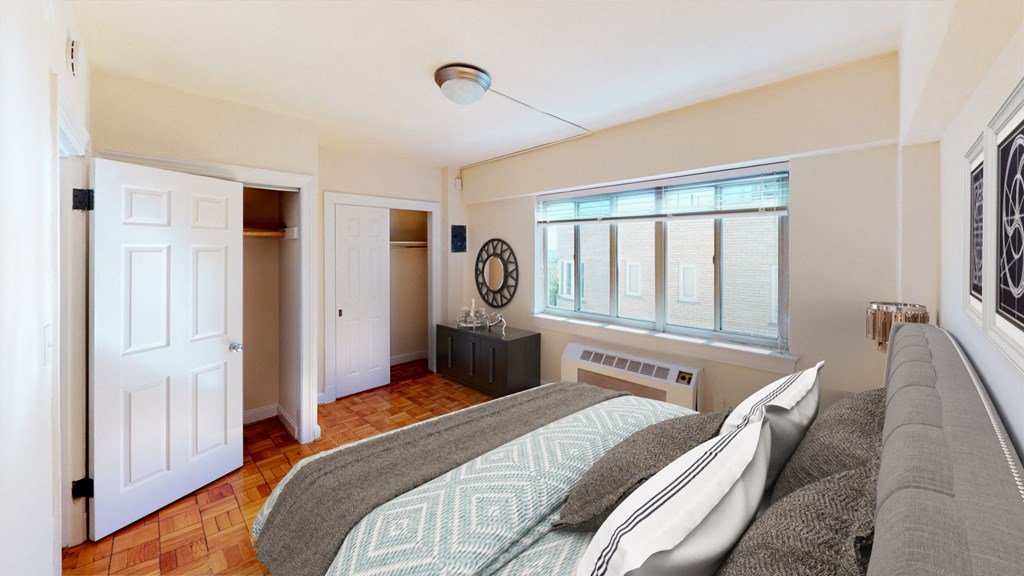 Bedroom with bed, nightstands, large windows, and large closet at sherry Hall apartments in washington dc