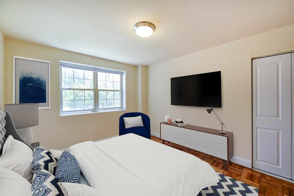 bedroom with bed, nightstands, large windows, parquet flooring, dresser and tv at shipley park apartments in washington dc