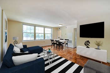 living area with sofa, coffee table, credenza, tv , large windows and view of dining area at shipley park apartments in washington dc - Photo Gallery 3