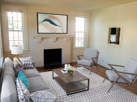 A living room with a fireplace and a painting above it.