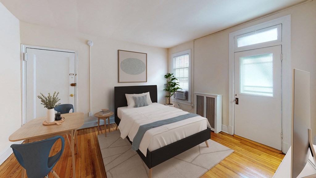 A bedroom with a bed, a table, and a chair.