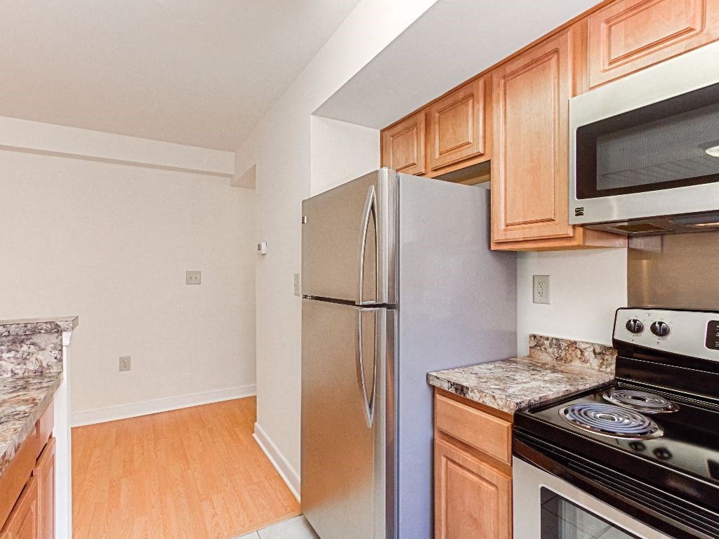 kitchen with stainless steel appliances and wood cabinets at the oaks apartments in washington dc
