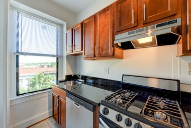 kitchen with stainless steel appliances, wood cabinetry and large window at the shawmut apartments in washington dc