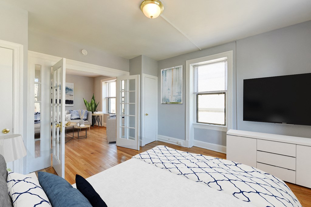 bedroom with bed, dresser, tv, hardwood flooring, french doors, and large windows at the shawmut apartments in washington dc