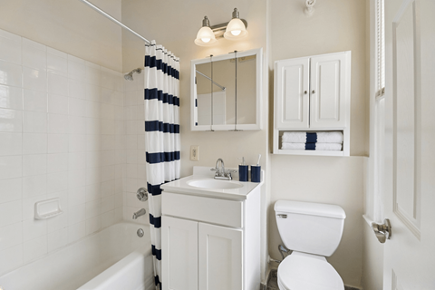 A white bathroom with a striped shower curtain.