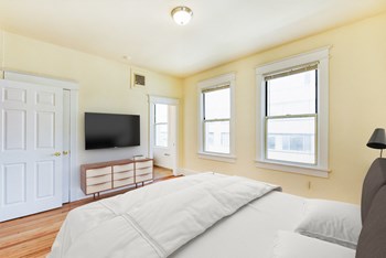 Bedroom with bed, dresser, tv, and large windows  at twin oaks apartments columbia heights washington dc - Photo Gallery 7
