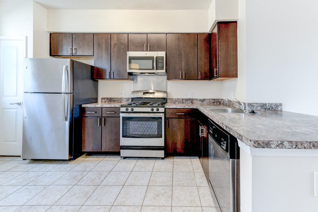 kitchen with espresso cabinetry, breakfast bar and stainless steel appliances at sheridan station south townhomes in washington dc