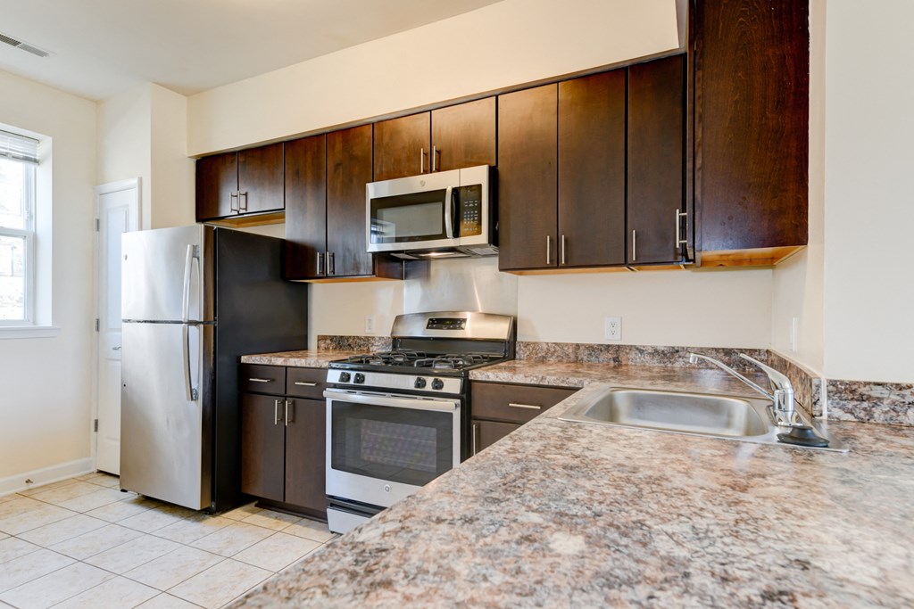 kitchen with espresso cabinetry, breakfast bar and stainless steel appliances at sheridan station south townhomes in washington dc