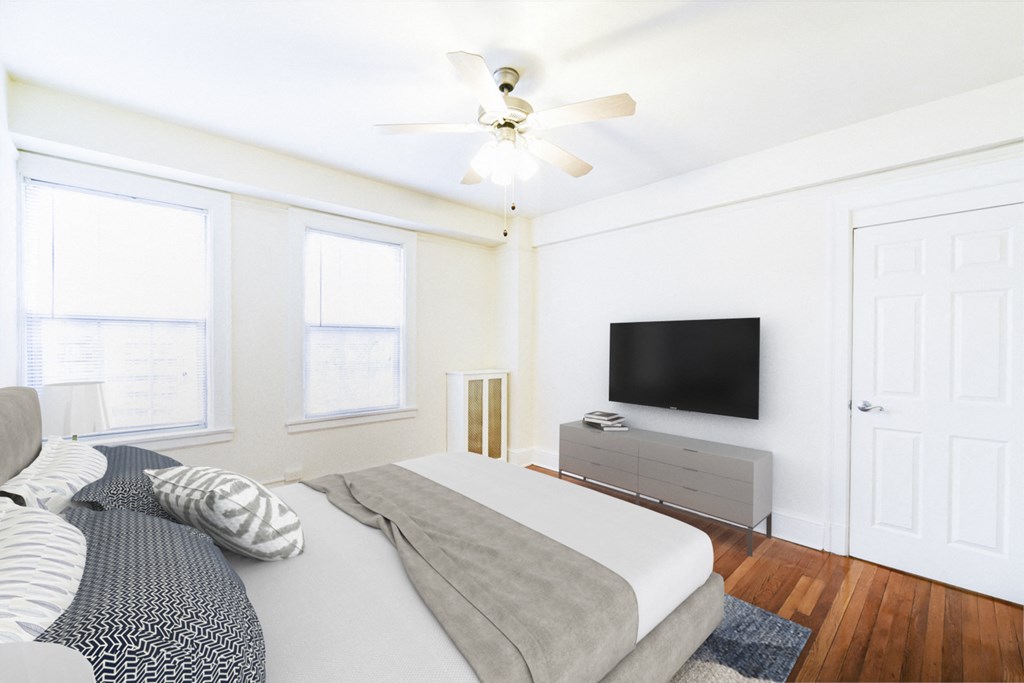 bedroom with bed, dresser, tv, hardwood floors, large windows , and ceiling fan at wakefield hall apartments in washington dc