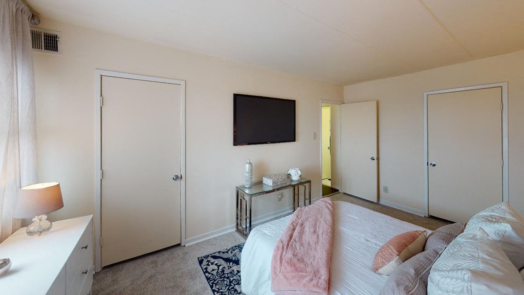 Bedroom with bed, dresser, tv, and closet at washington view apartments in washington dc