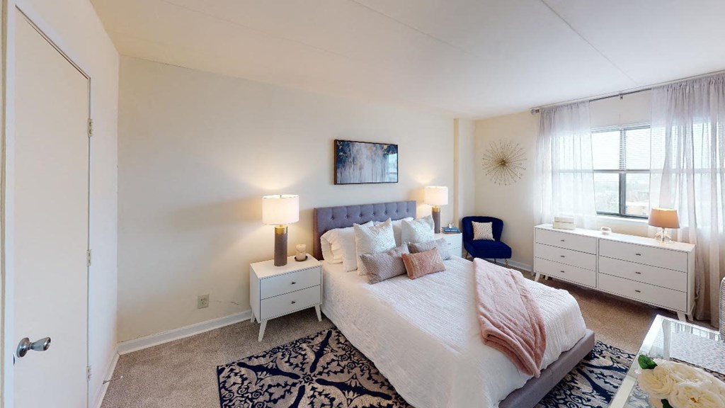 Bedroom with nightstands, bed and large windows at washington view apartments in southeast dc