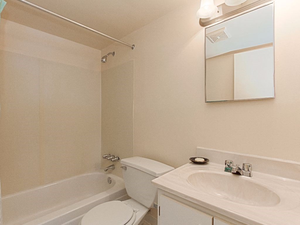 bathroom with mirror, tub, toilet and vanity at washington view apartments in southeast dc