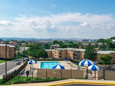 view of pool with chaise lounge chairs and umbrellas at washington view apartments in south east dc