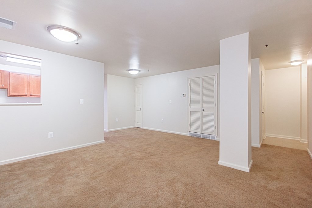 vacant living area with plush carpeting, and view of kitchen at whitelaw apartments in washington dc