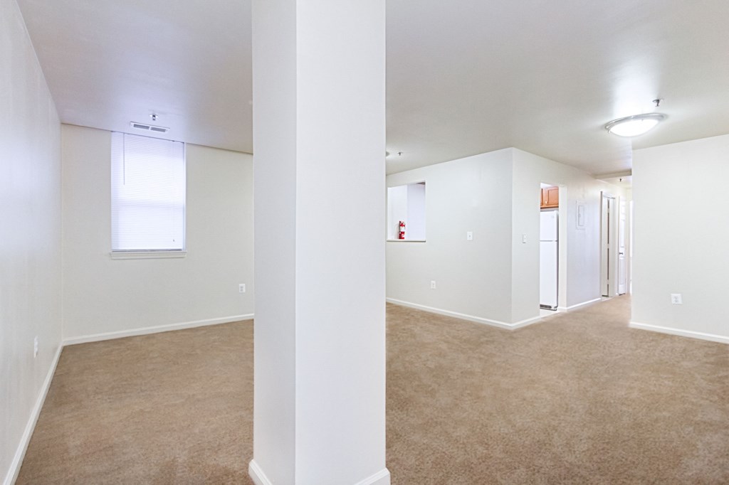 vacant living area with plush carpeting, windows and view of kitchen at whitelaw apartments in washington dc