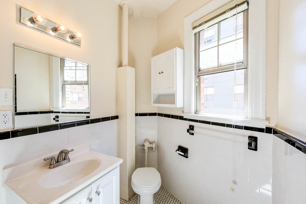 bathroom with toilet, sink, vanity, mirror and cabinet at the frontenac apartments in van ness washington dc