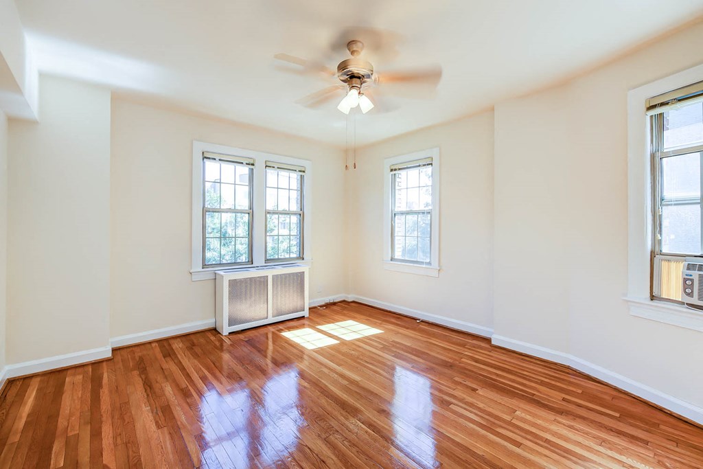 vacant bedroom with hardwood floors, ceiling fan and large windows at the frontenac apartments in van ness washington dc