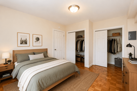 A bedroom with a large bed and a wooden dresser.