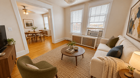 A living room with a green armchair, a white sofa, and a wooden coffee table.