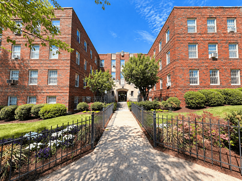 A long, narrow alleyway between two red brick apartment buildings.