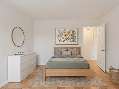 A bedroom with a bed, dresser, and a framed picture on the wall.