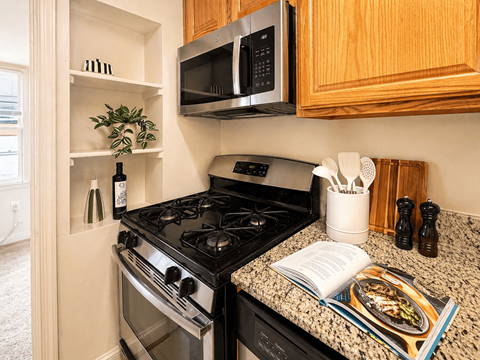 A kitchen with a black stove and a black microwave above it.