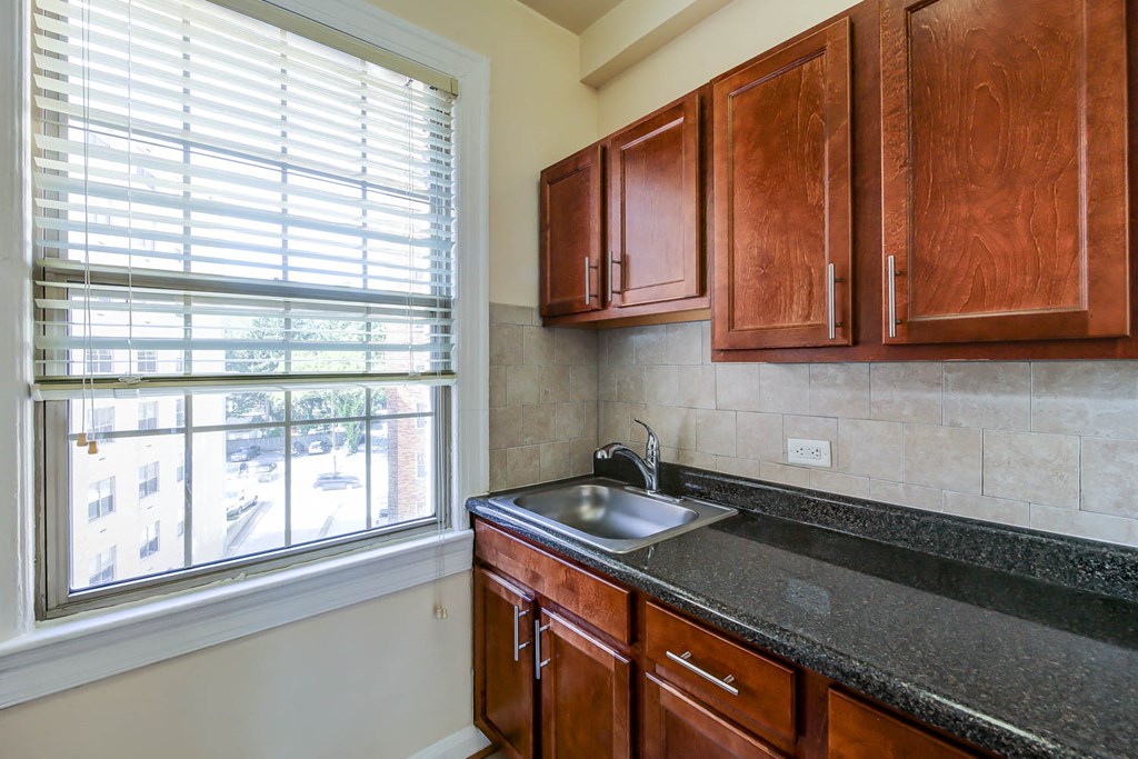 kitchen with large window, oak cabinetry and tile backsplash at the frontenac apartments in van ness washington dc