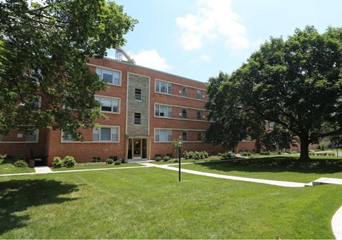 A red brick apartment building with a tree in front.