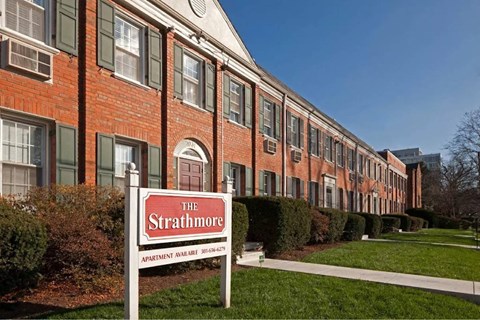 A red brick building with a sign that says The Strathmore Apartment Apartments.