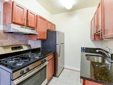 kitchen with wood cabinetry, gas range, and stainless steel appliances sherry hall apartments in washington dc