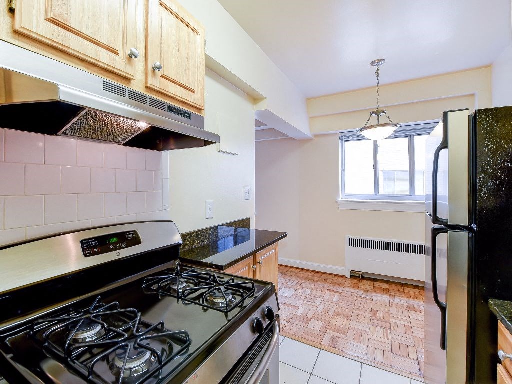 kitchen with wood cabinetry, gas range, and stainless steel appliances sherry hall apartments in washington dc