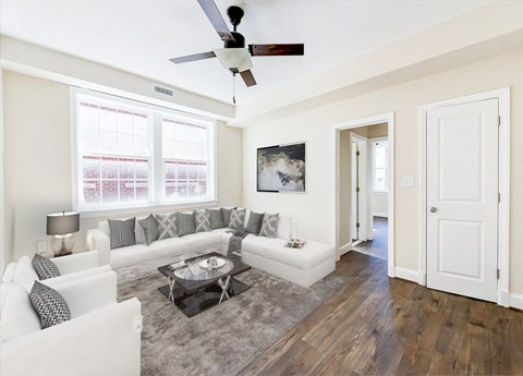 a living room with white couches and a ceiling fan