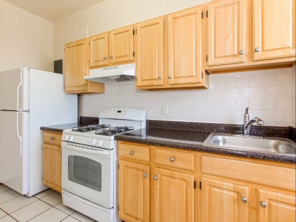 a kitchen with wooden cabinets and white appliances at the calverton apartments in washington dc