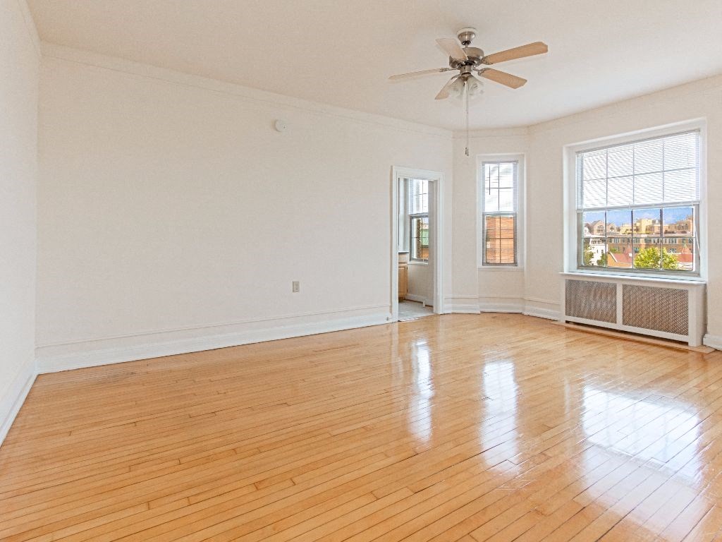 an empty living room with hardwood floors and a ceiling fan at the calverton apartment building in washington dc