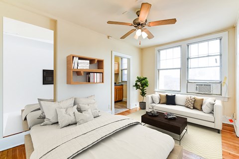 studio apartment showing sofa, bed, ceiling fan, large windows and view of kitchen at the foreland apartments in washinton dc