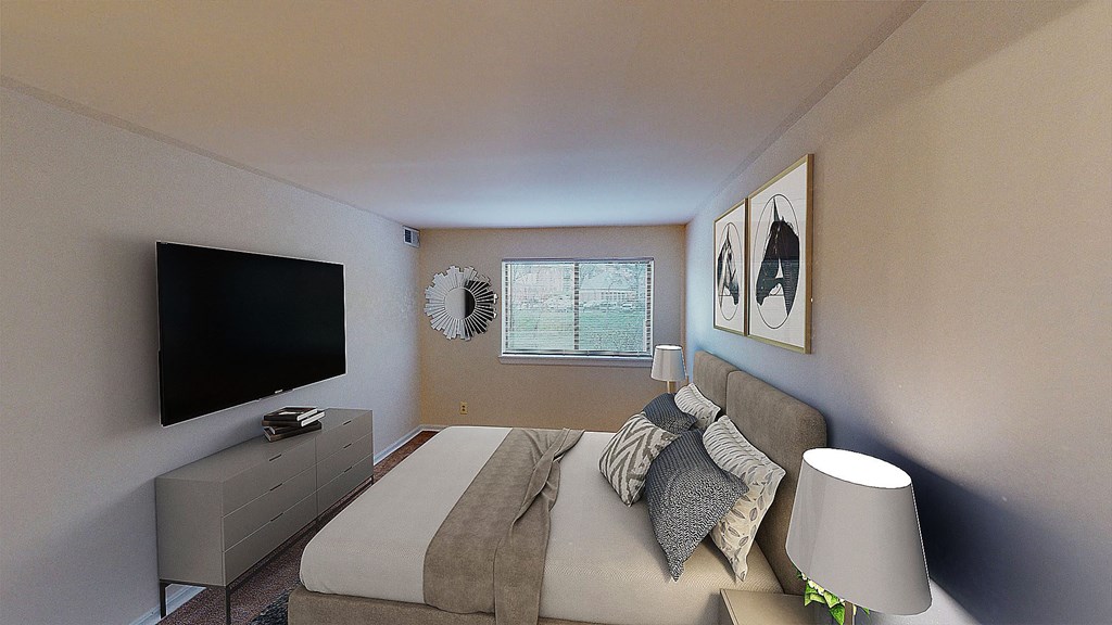Bedroom with dresser, tv, bed and large windows at washington view apartments in southeast dc