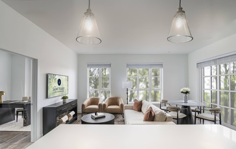 A living room with a white couch and a painting of a tree on the wall.