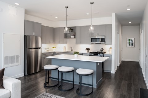 A kitchen with a bar stool and a fridge.