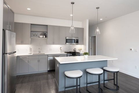 A modern kitchen with a bar stool and a refrigerator.
