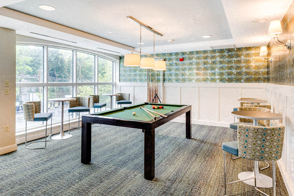 A room with a pool table and chairs.
