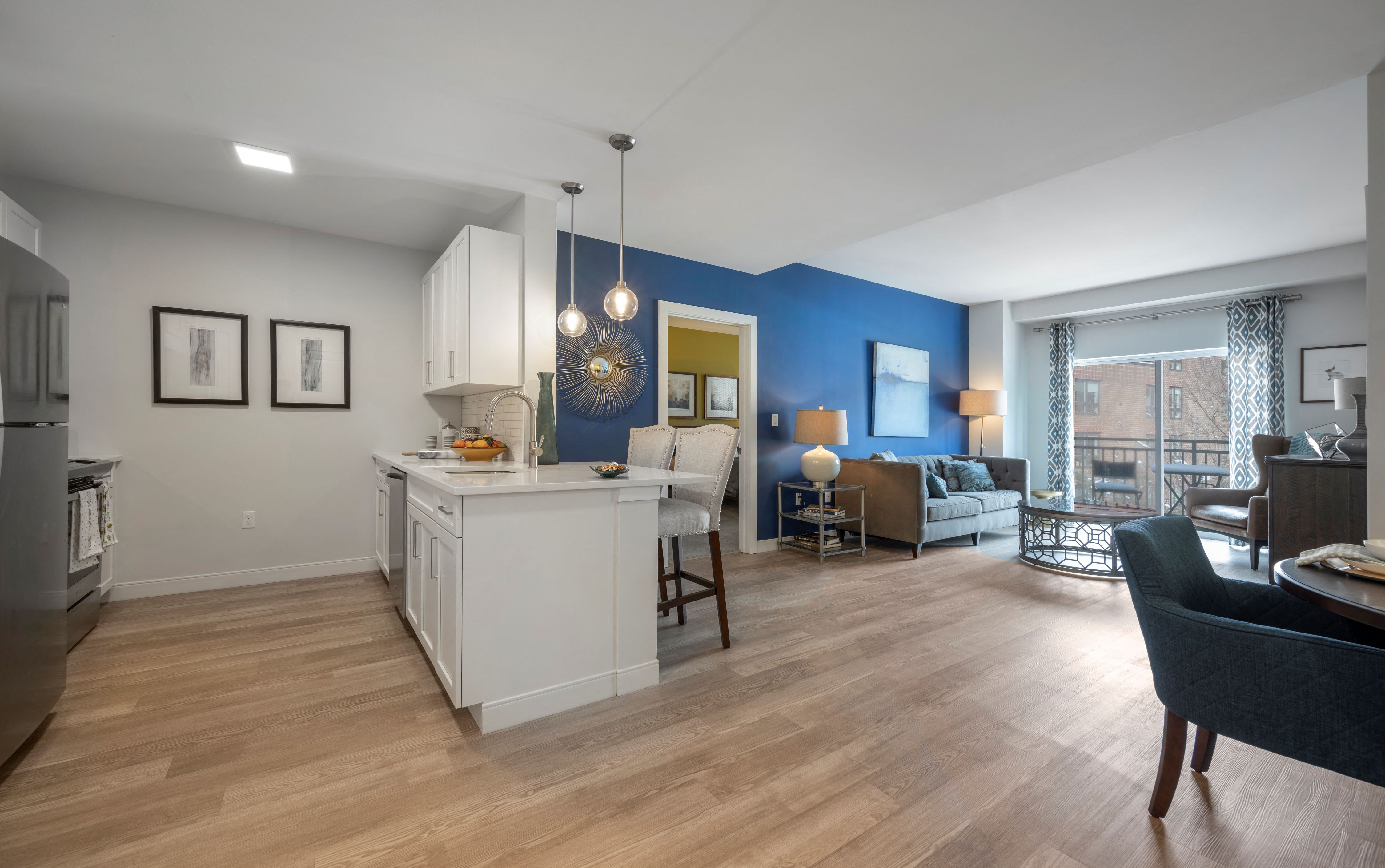 A kitchen with a white island and a dining table with chairs.