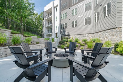 A patio with black chairs and a fire pit in front of a building.