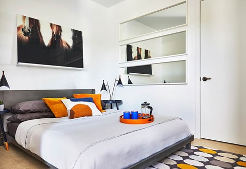 A bedroom with a bed, pillows, a tray, and a painting on the wall.