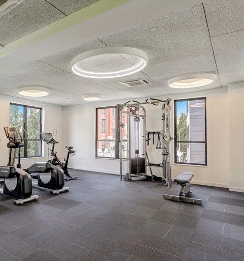 A spacious gym with a variety of equipment including treadmills, elliptical machines, and a weight bench.