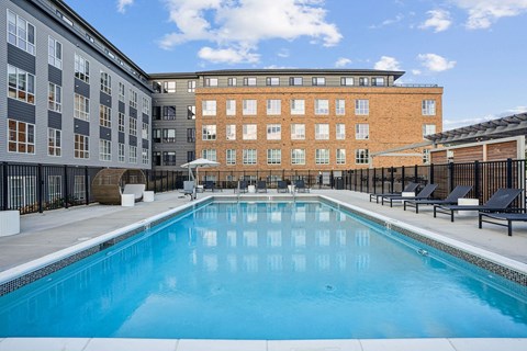 A large swimming pool in front of a building with a fence around it.