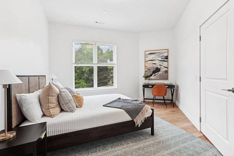A bedroom with a large bed and a desk with a chair.